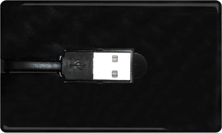 Schwarze externe Festplatte mit angeschlossenem USB-Kabel auf dunklem Hintergrund