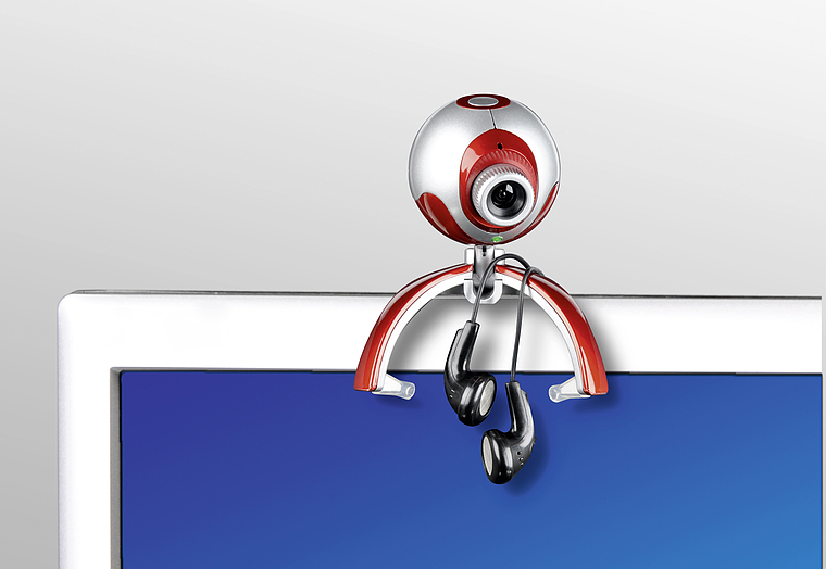 Webcam im ungewöhnlichen Design mit Kopfhörern, oben auf einem Computerbildschirm befestigt