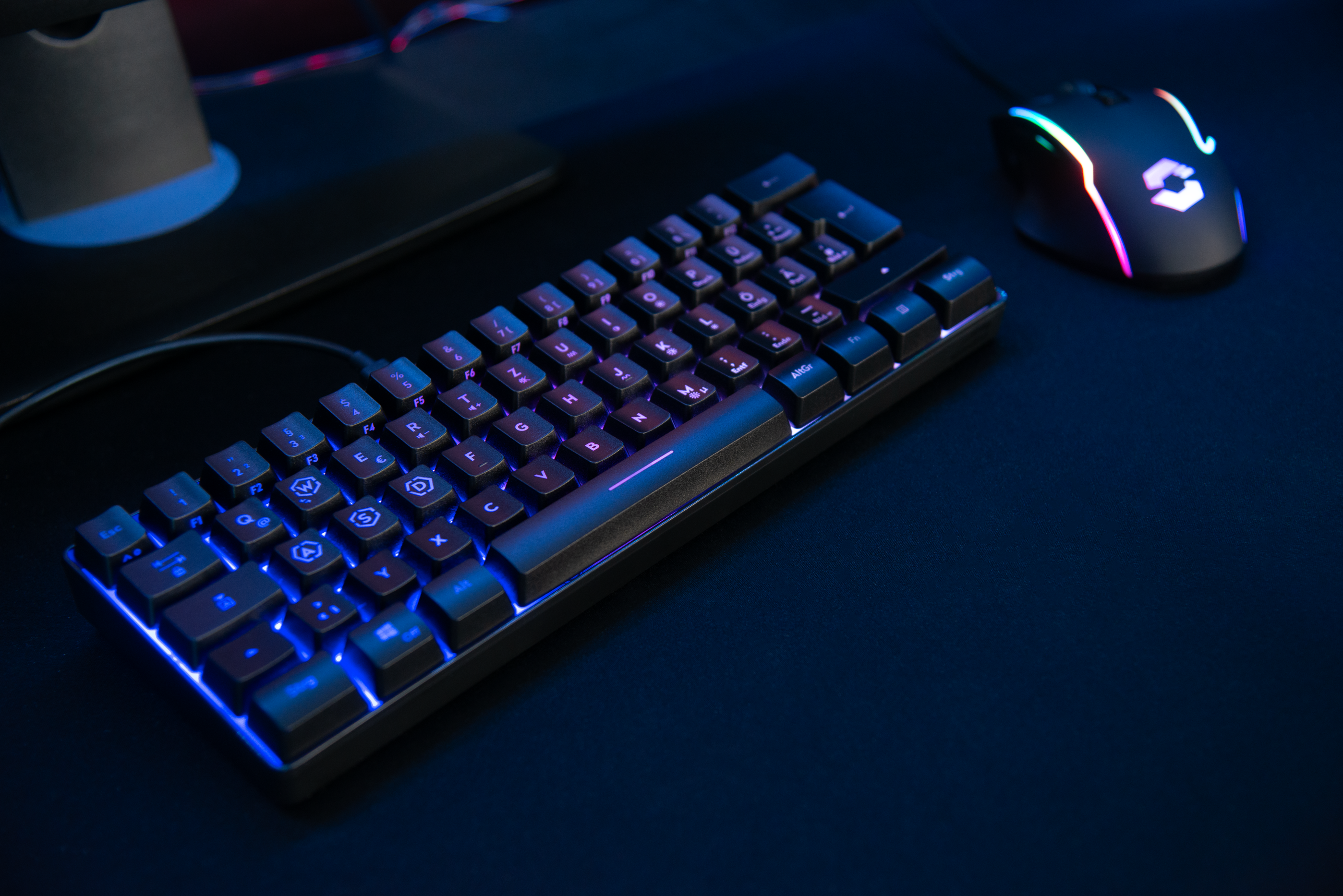 Beleuchtete mechanische Gaming-Tastatur und RGB-Maus auf schwarzem Schreibtisch