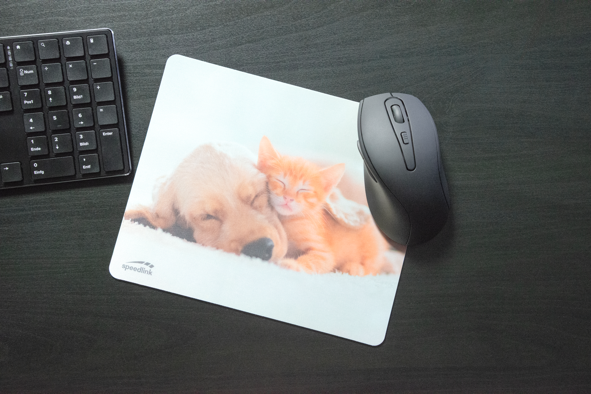 Mauspad mit Motiv eines schlafenden Hundes und einer Katze neben einer schwarzen Computermaus und Tastatur auf dunklem Schreibtisch