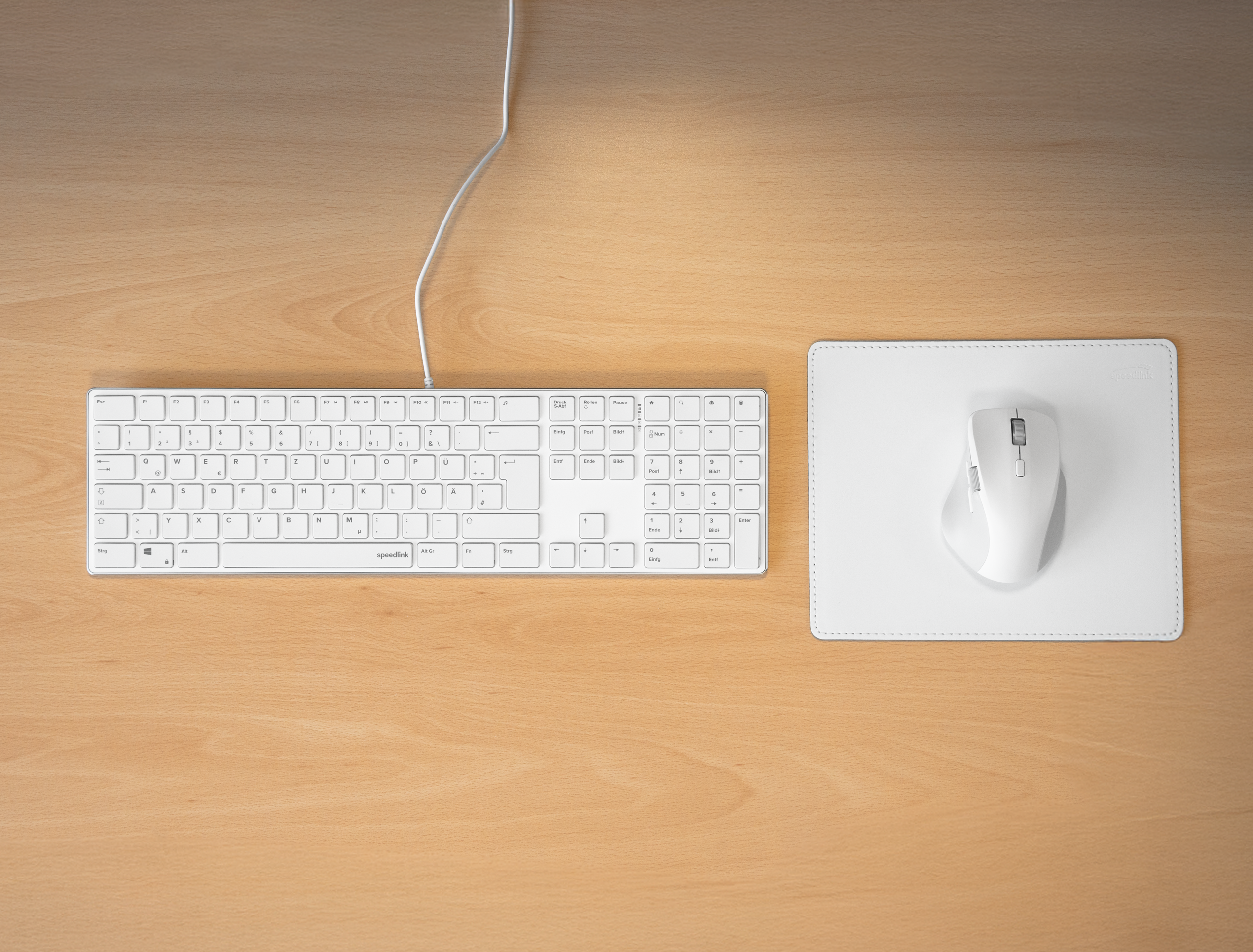 Weiße Computertastatur und kabellose Maus auf weißem Mauspad auf einem Holzschreibtisch
