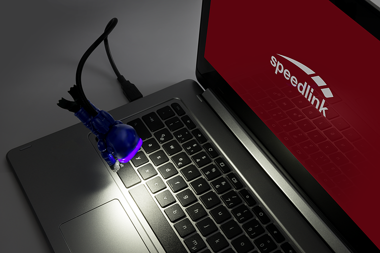 Kleine blaue USB-Lampe in Form einer Figur leuchtet die Tastatur eines Laptops mit speedlink-Logo aus