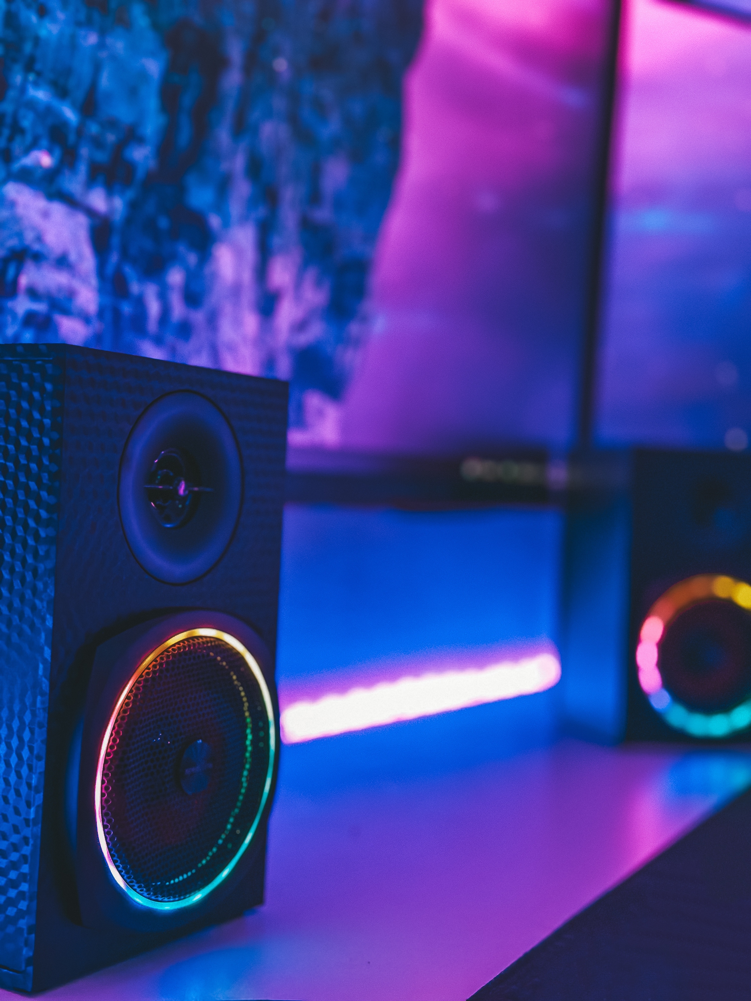 Nahaufnahme eines modernen Gaming-Lautsprechers mit RGB-LED-Beleuchtung auf einem Schreibtisch vor Monitor