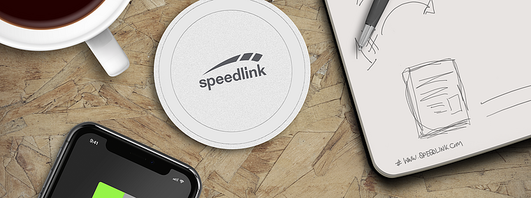 Weißes Speedlink Wireless Charger Ladepad auf Holzschreibtisch, daneben Smartphone, Notizblock und Kaffee
