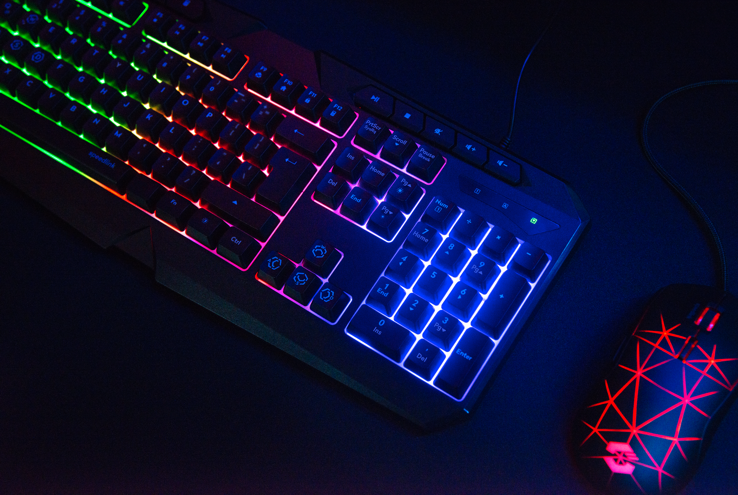 Beleuchtete Gaming Tastatur mit farbigem RGB-Licht und passender Gaming Maus auf dunklem Untergrund